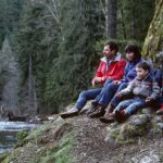 Famille en pause au bord d une riviere pendant une balade nature avec des enfants.