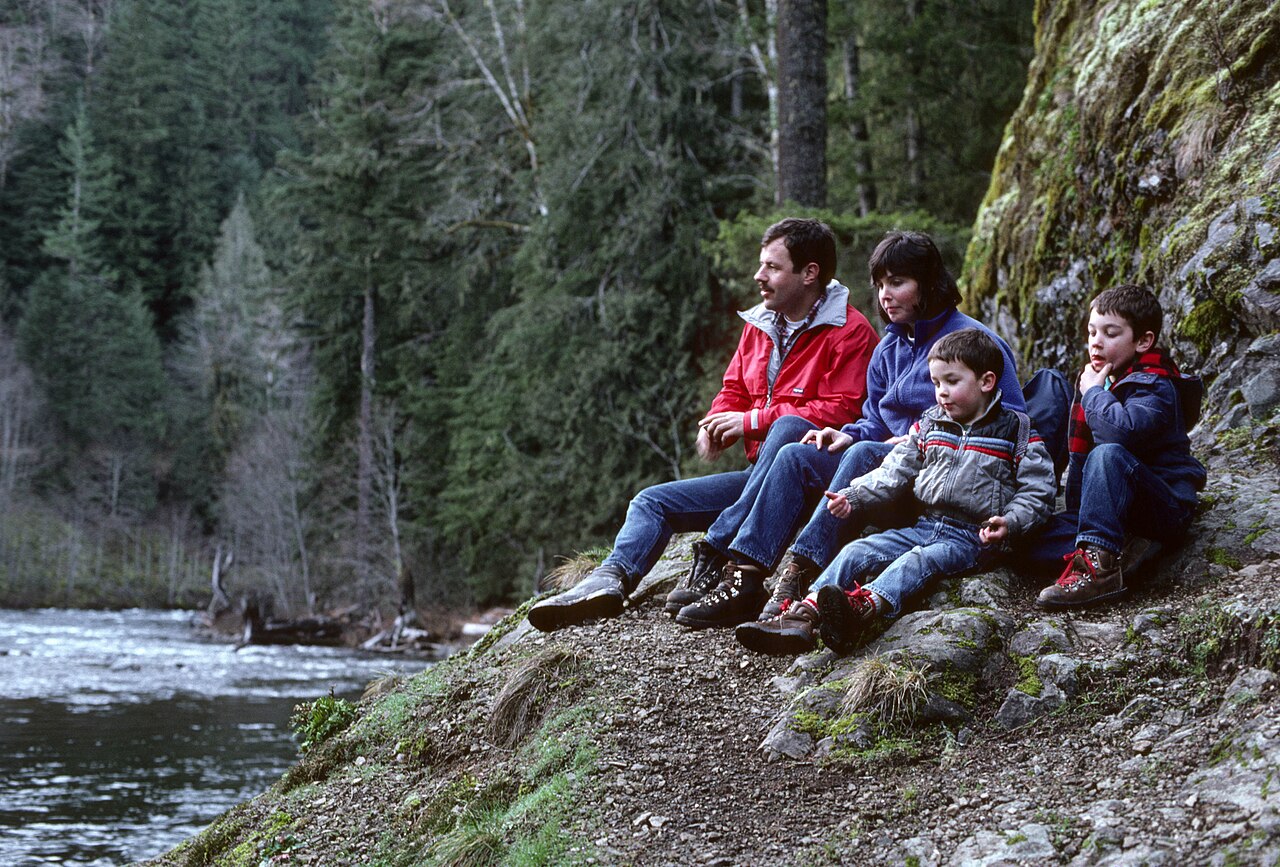 Famille en pause au bord d une riviere pendant une balade nature avec des enfants.